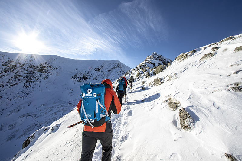 People hiking up a mountain in the snow