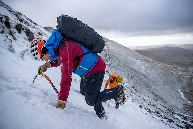 A man using an ice axe to climb mountain